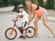 Mother helping her son ride a bicycle in a sunny outdoor setting. Bonding and learning experience.