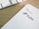 Close-up of a to-do list next to a computer keyboard on a desk.